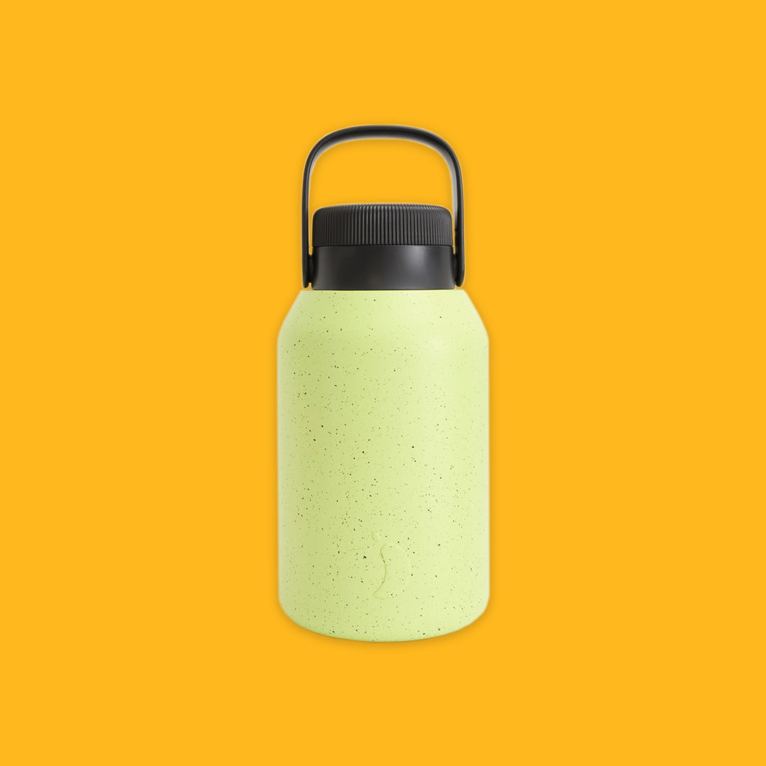 Green textured water bottle with black cap on a yellow background