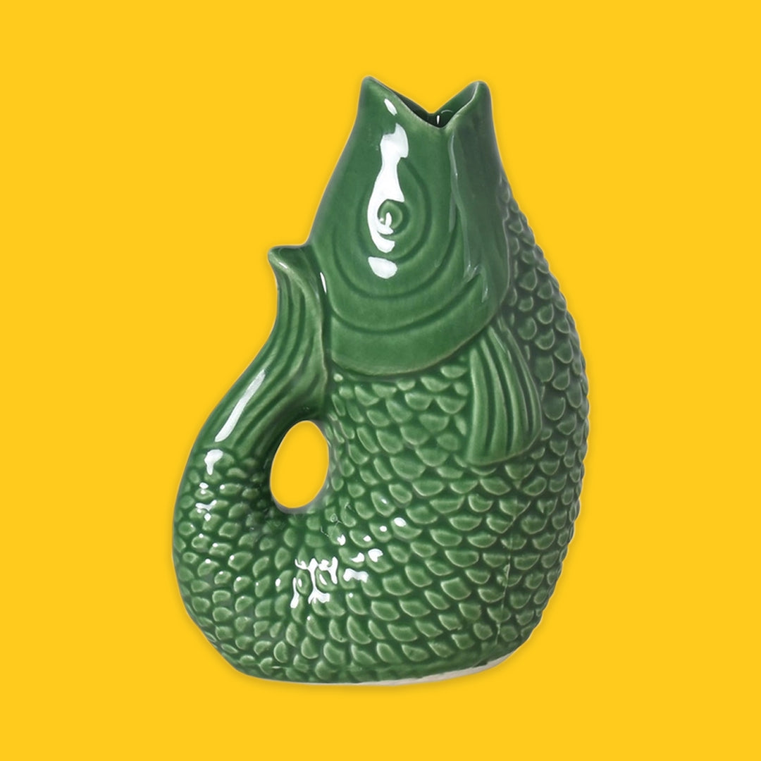 Green ceramic fish-shaped vase on a yellow background