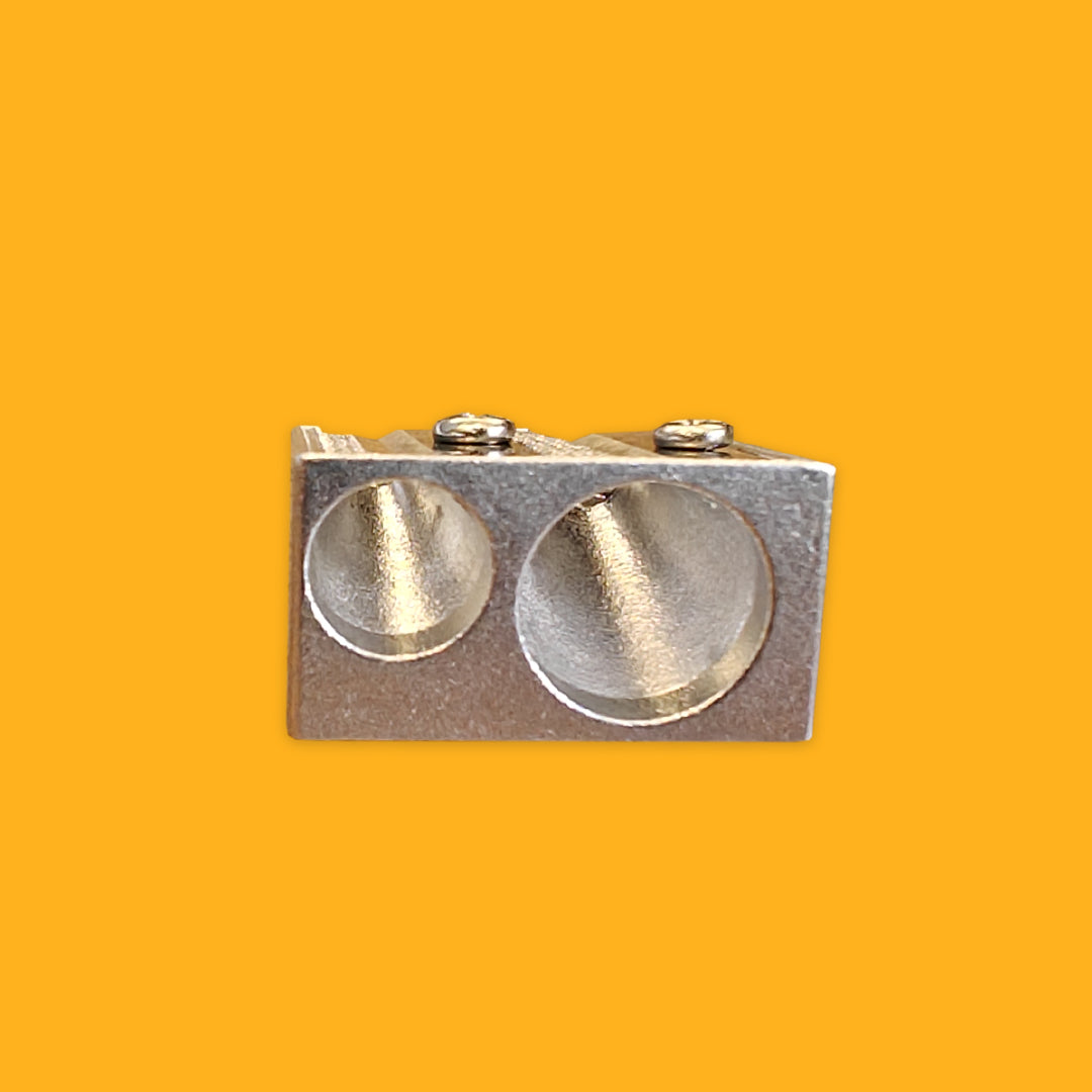 Metallic sharpener with two circular holes on a yellow background