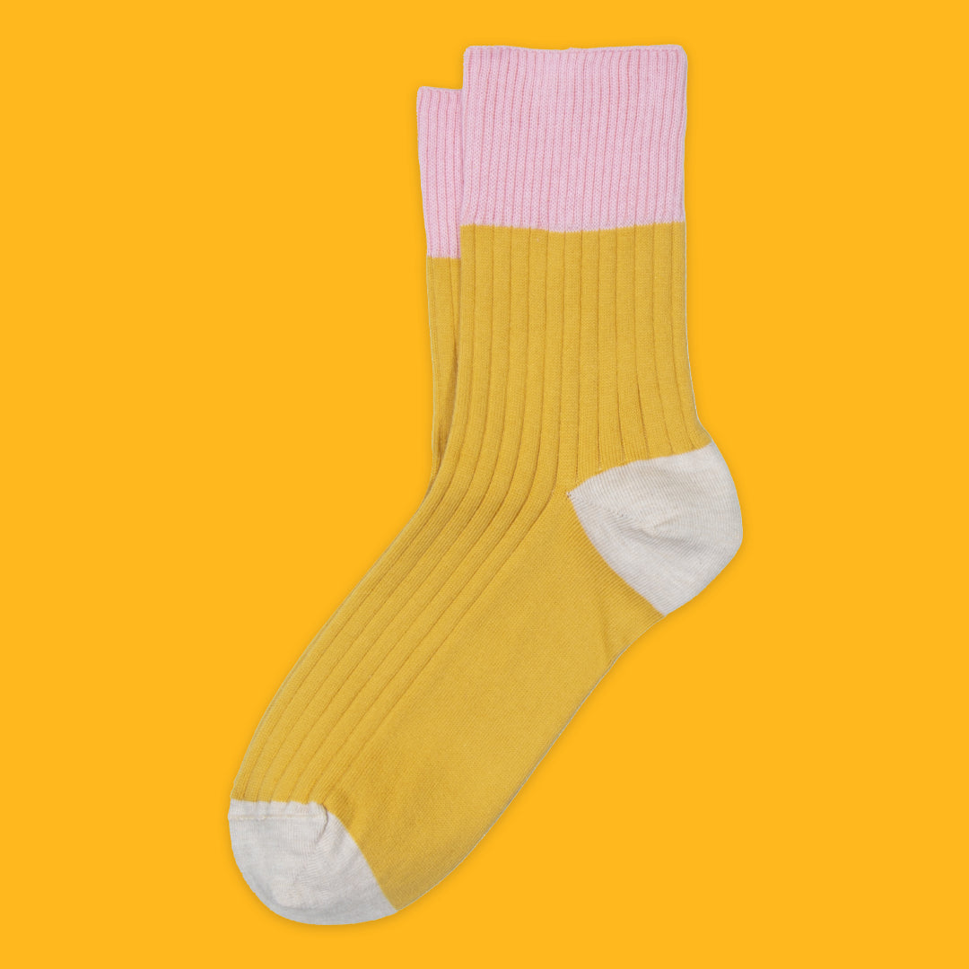 Yellow sock with pink top and white toes on a yellow background