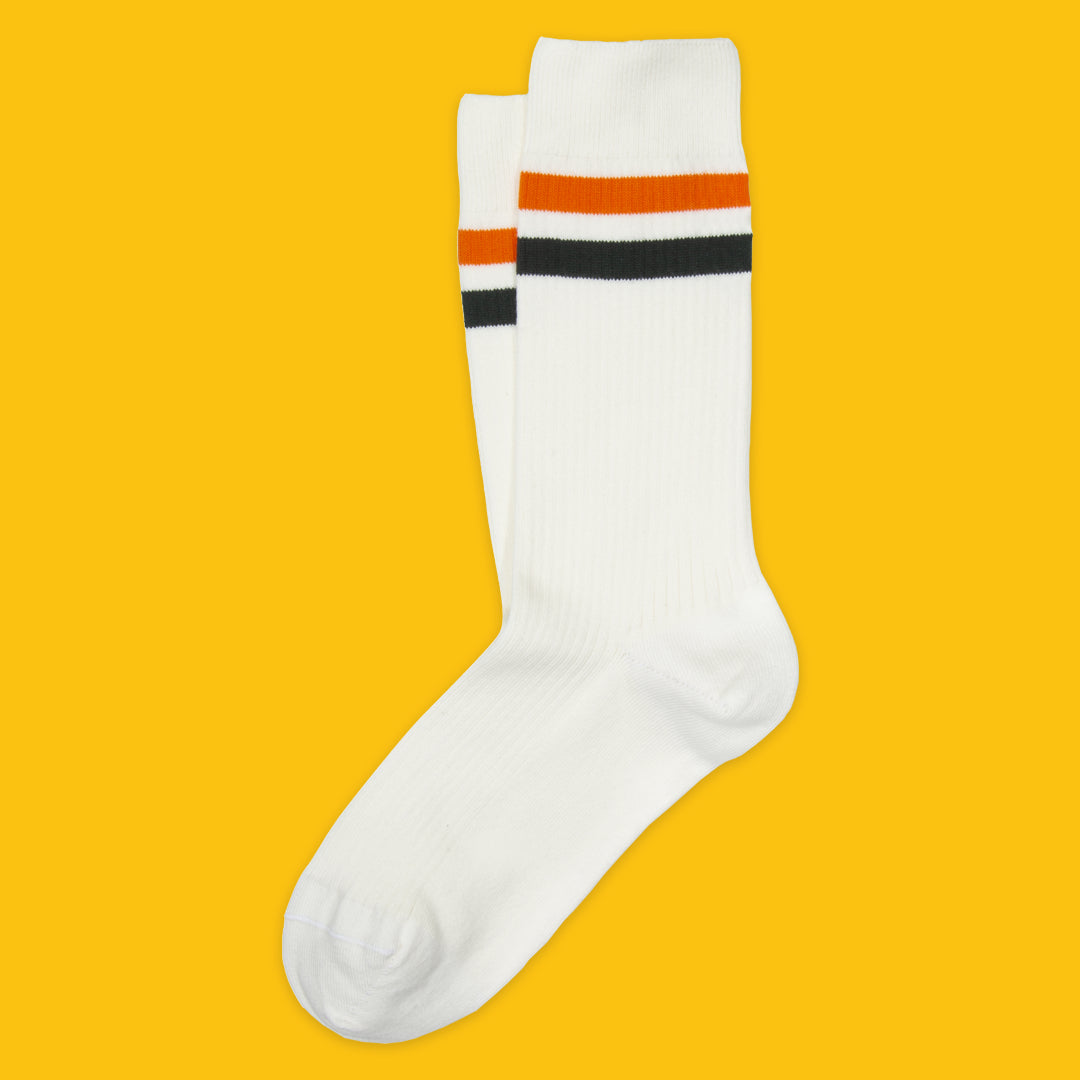 White sock with orange and green stripes on a yellow background