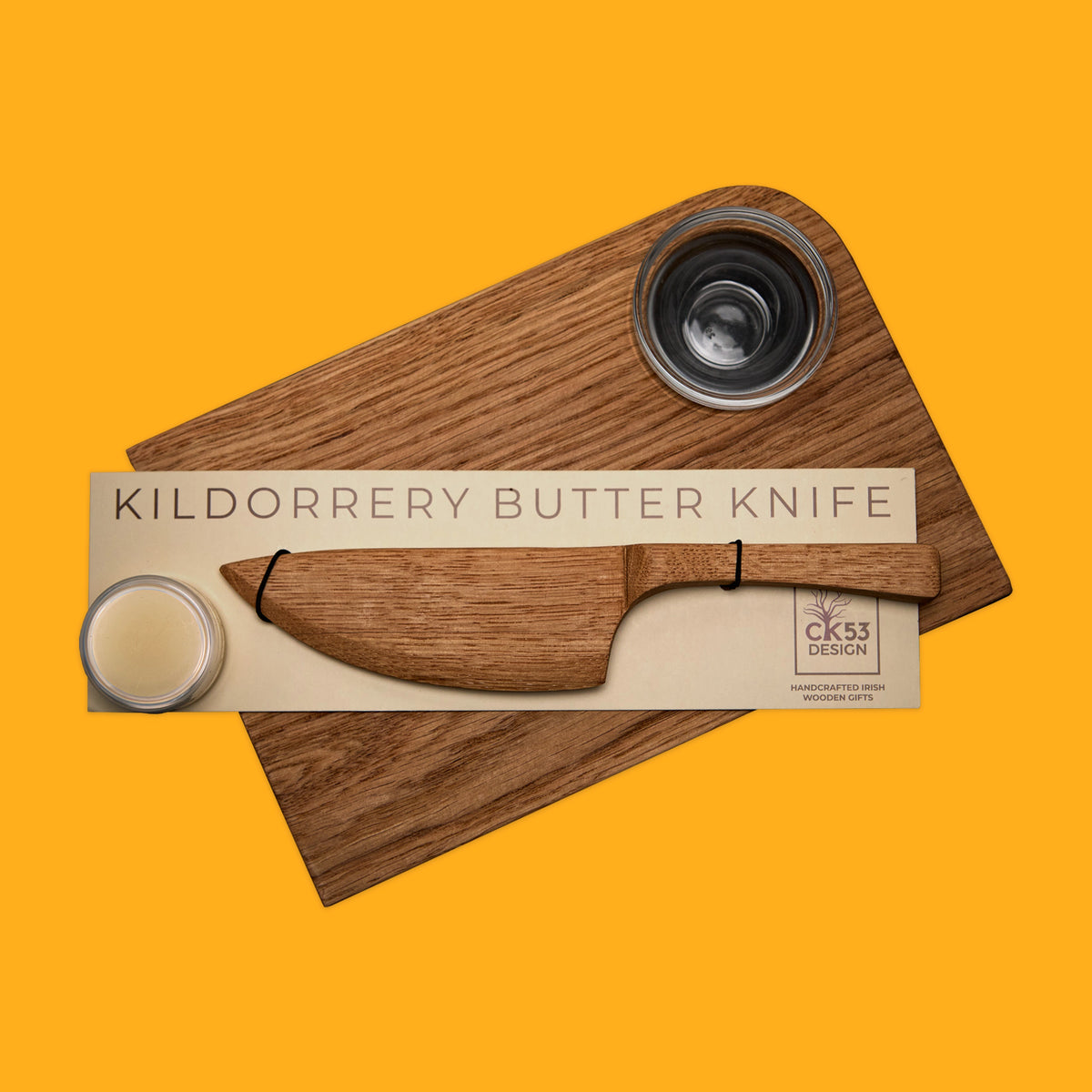Matching oak butter knife and board on a yellow background
