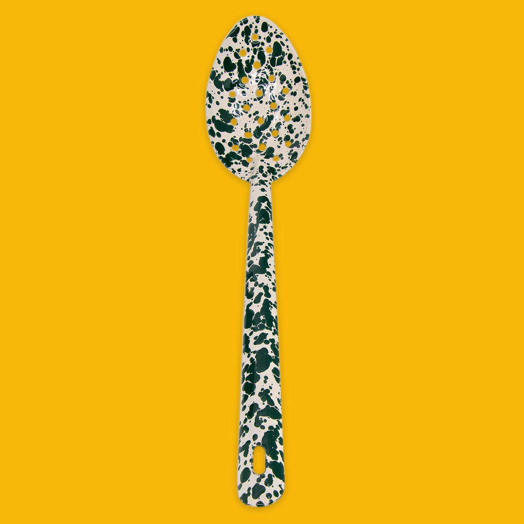 Enamel Splatter Green and Cream slotted spoon on a yellow background