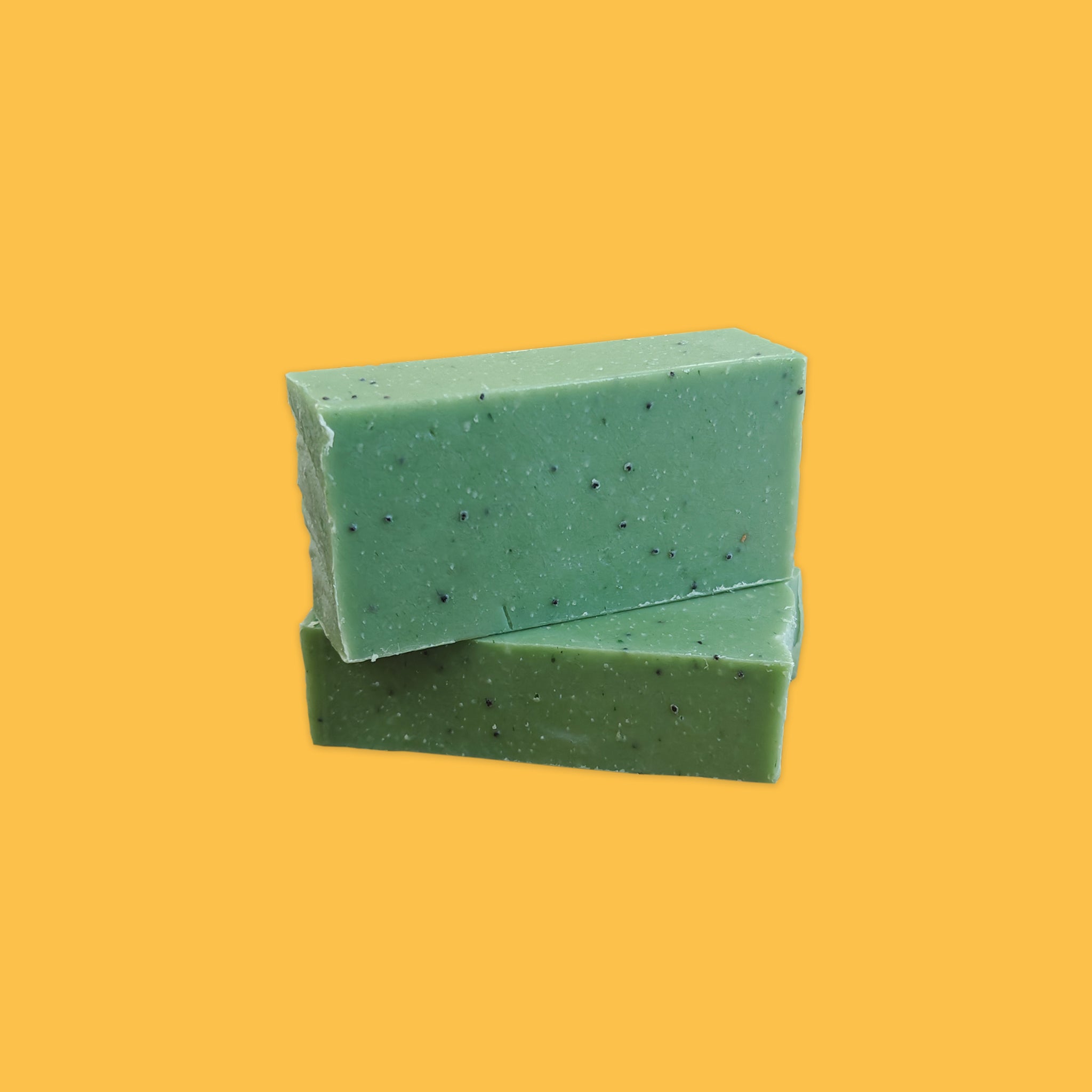Two Green Poppy Scrub Soaps stacked on each other with a yellow background