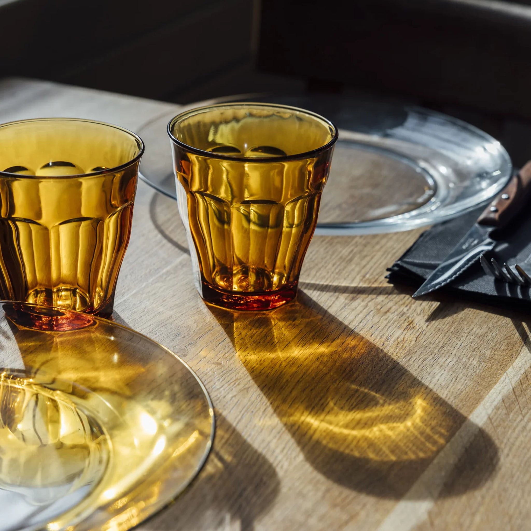 Two amber glasses on a wooden table with a blurred background