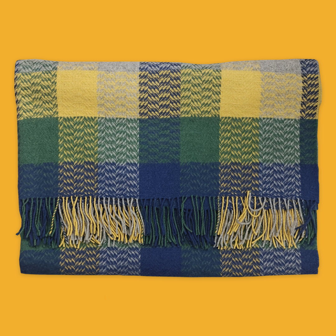 Plaid blanket with green, blue, and yellow colours on a yellow background