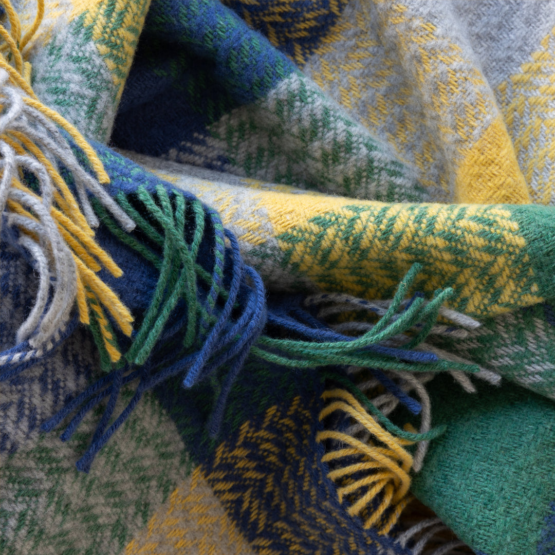 Close-up of a colourful woven fabric with fringes in blue, green, and yellow.