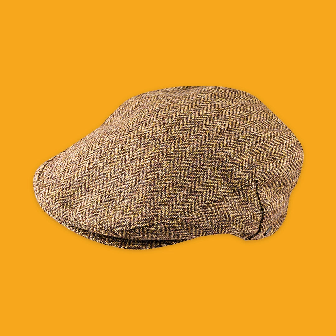 A classic flat cap in a brown and beige herringbone tweed pattern, presented on a solid orange background.