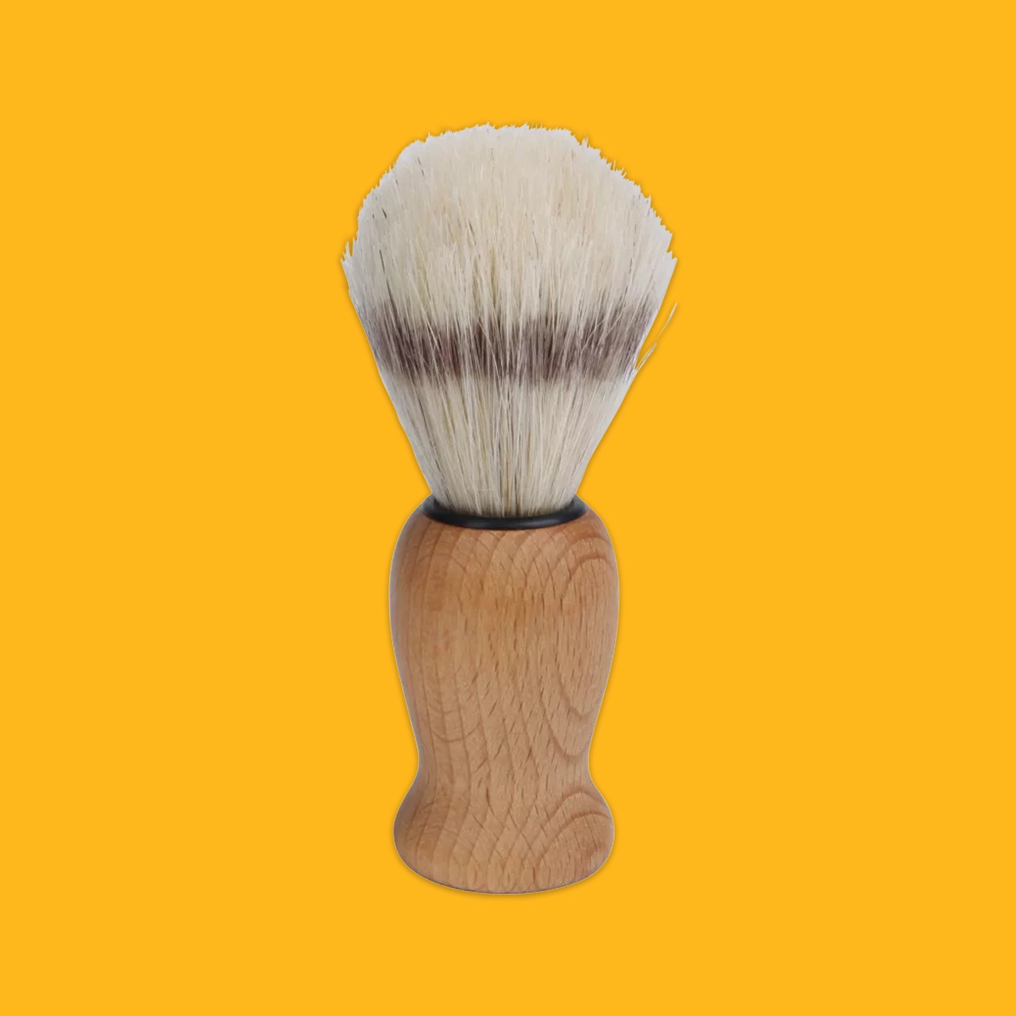 A shaving brush with a light brown wooden handle and white bristles featuring dark brown tips, centered against a solid yellow background.