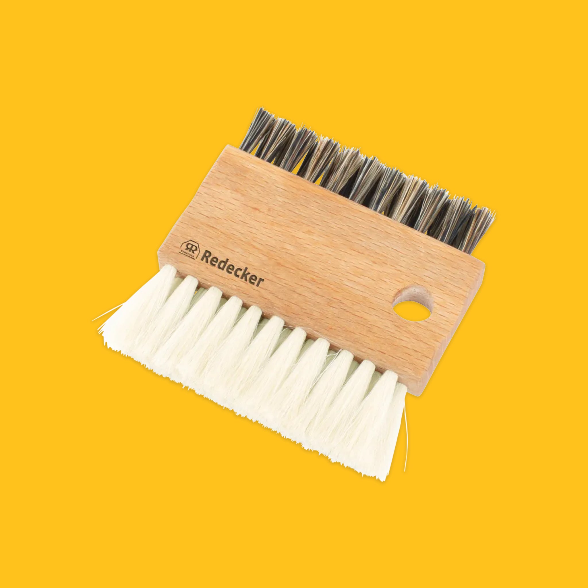 Wooden brush with bristle and soft brush heads on a yellow background, featuring the brand 'Redecker'.