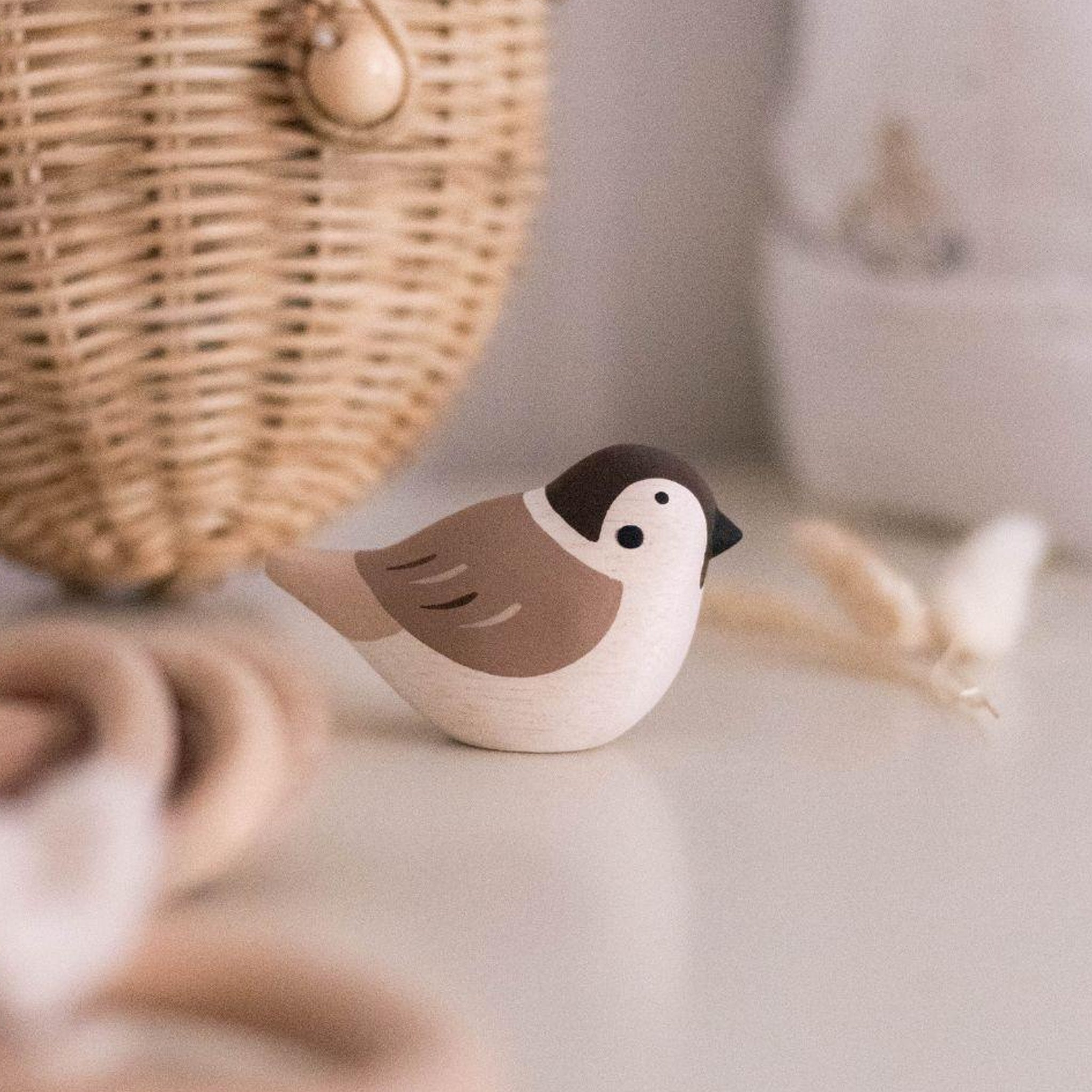 Wooden sparrow on a table beside a basket