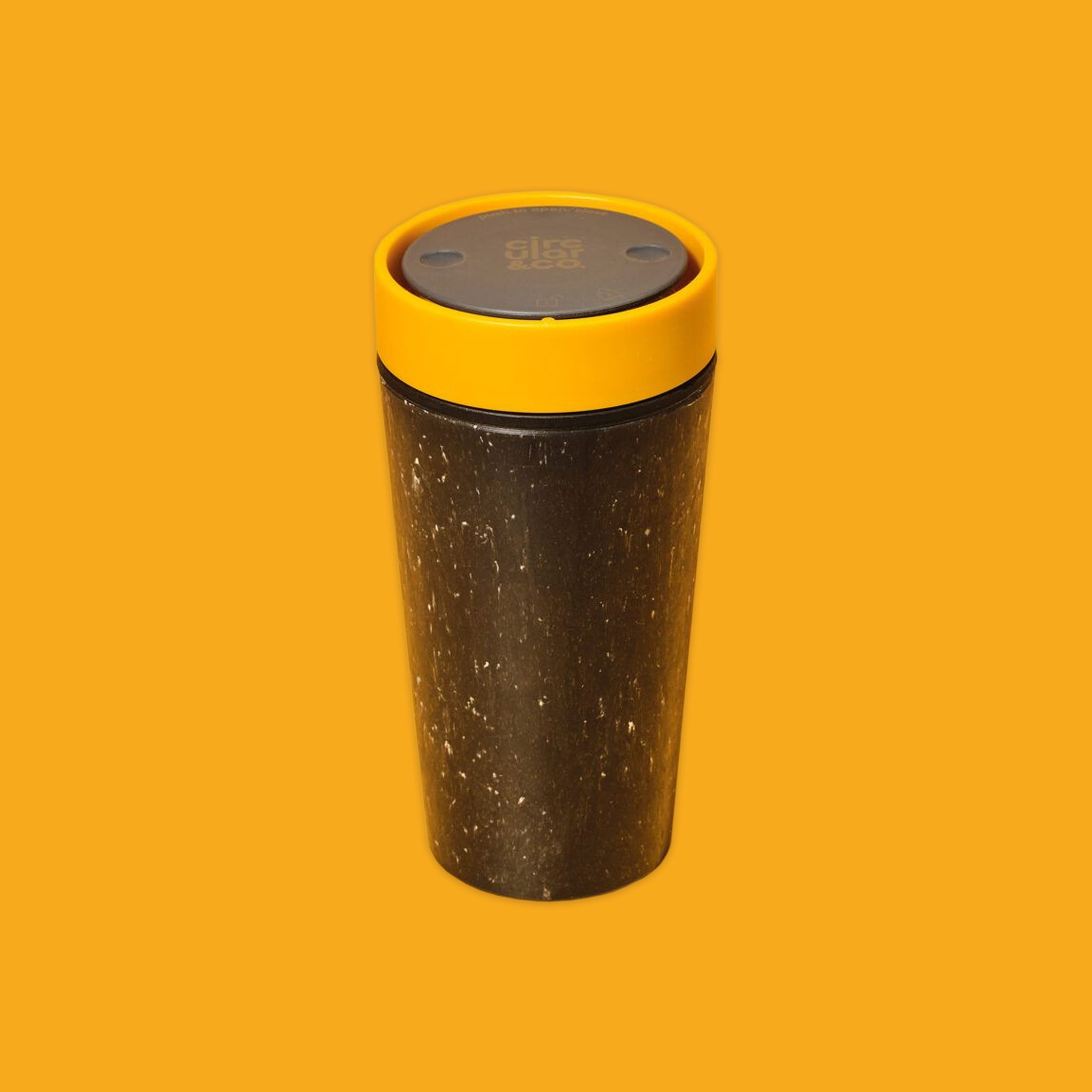Black travel mug with yellow lid on an orange background