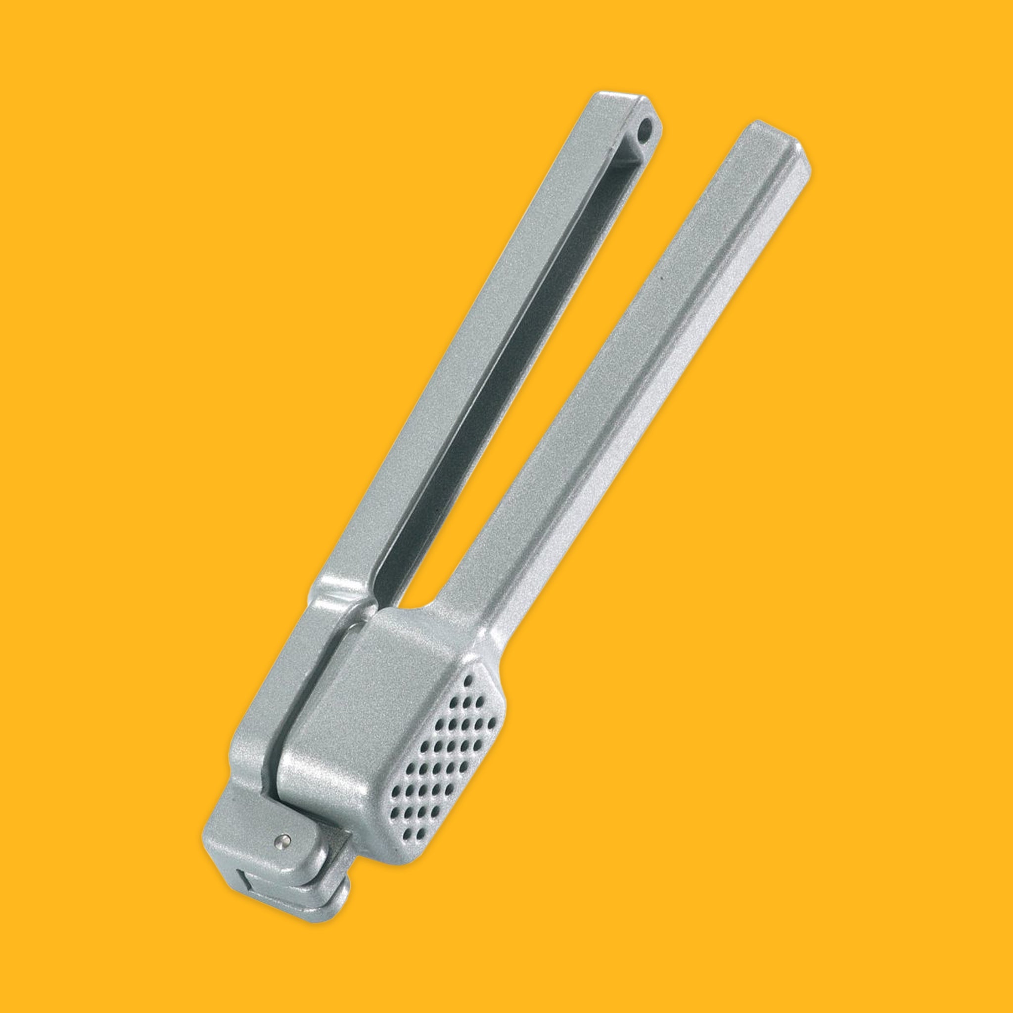 Metal garlic press on a yellow background
