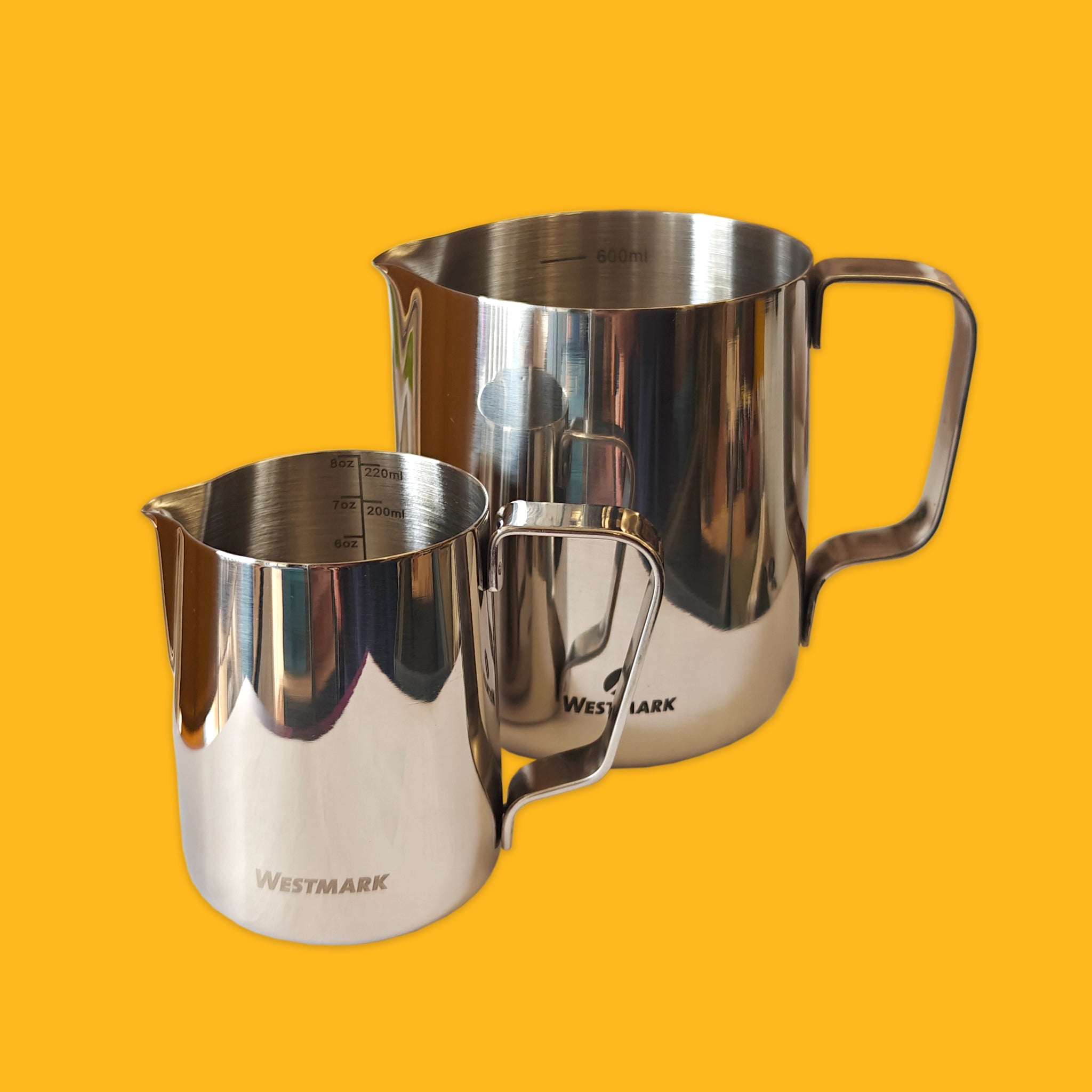 Two stainless steel pitchers with Westmark branding on a yellow background