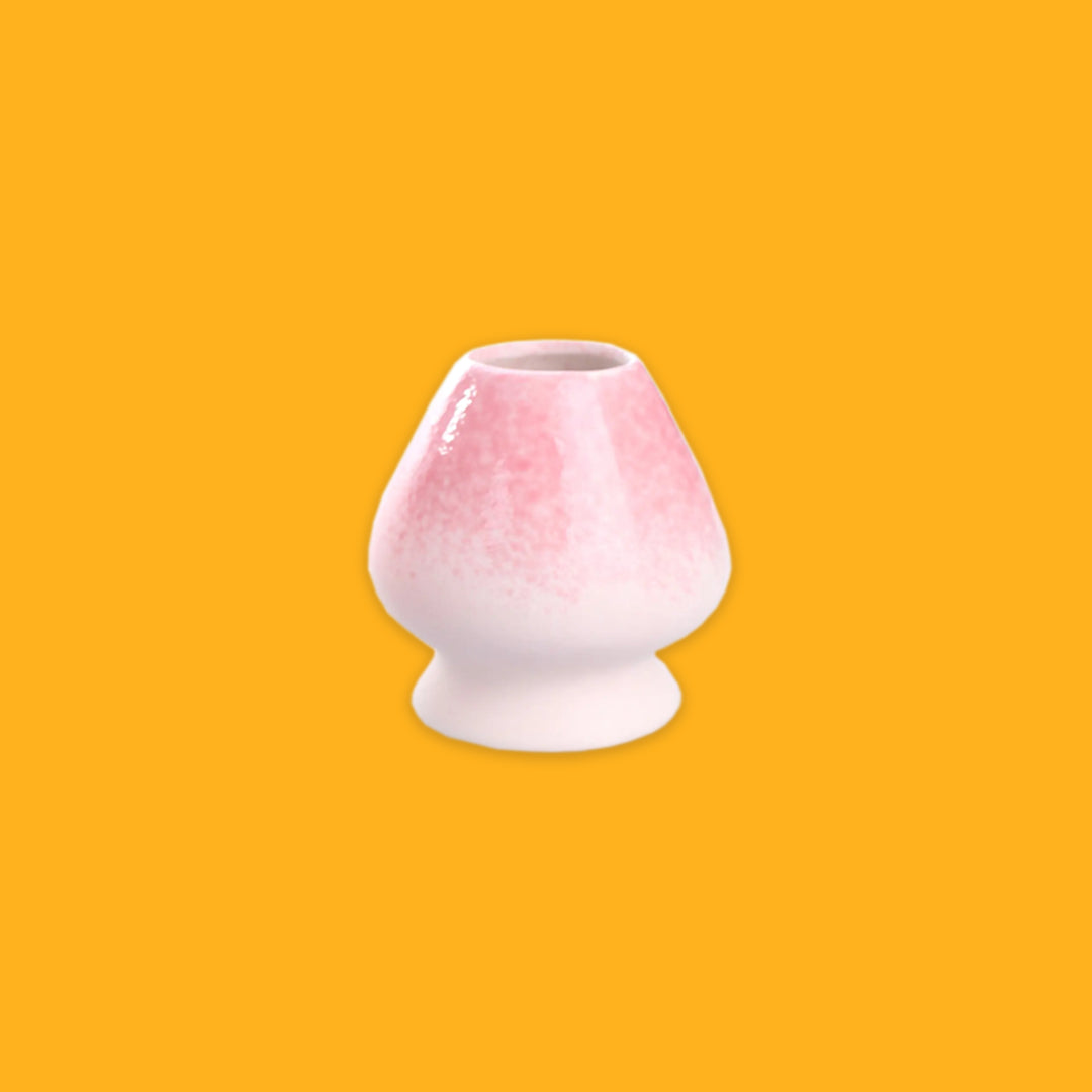 Pink and White porcelain whisk holder on a yellow background