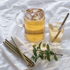 Iced-tea with bamboo straws on white table