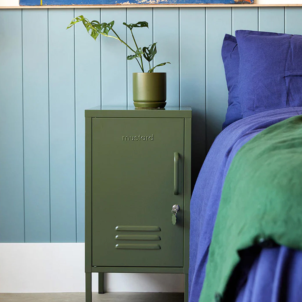 Mustard Made The Shorty in Olive beside a blue bed